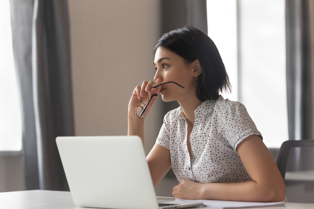 woman with laptop staring off in deep thought
